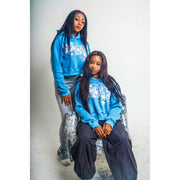 Two girls wearing blue hoodies with a design that shows "R3BIRTH EST '23" in a pink decorative style