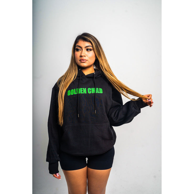 woman wearing a black hoodie with a design that shows "Golden Child" written in green