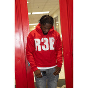man wearing a red crop hoodie with a design that shows 'R3B'